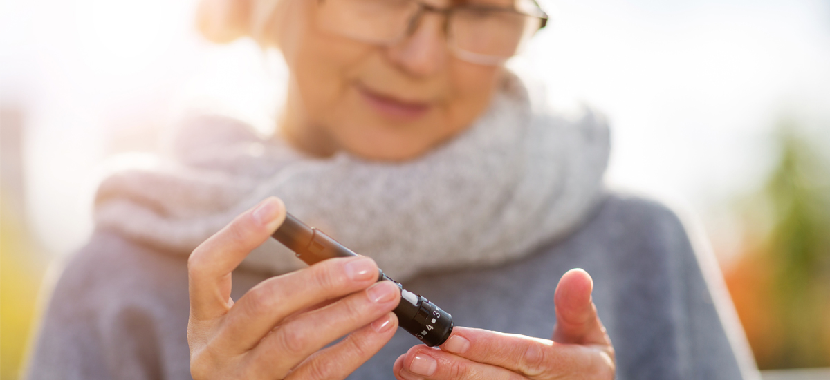 Mature woman using glucose monitor to check blood